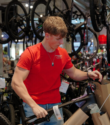 Ein Fahrradladenmitarbeiter in rotem Hemd montiert ein neues Mountainbike zum Verkauf.