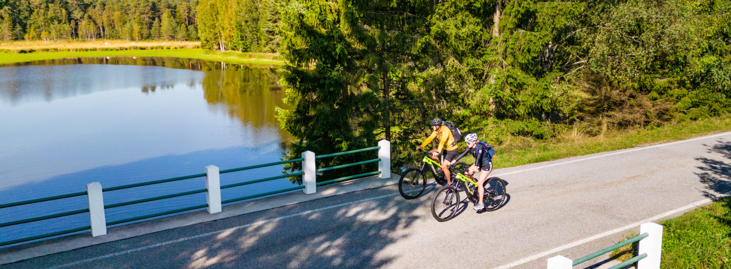 Zwei Fahrradfahrer fahren auf einer Brücke neben einem Teich