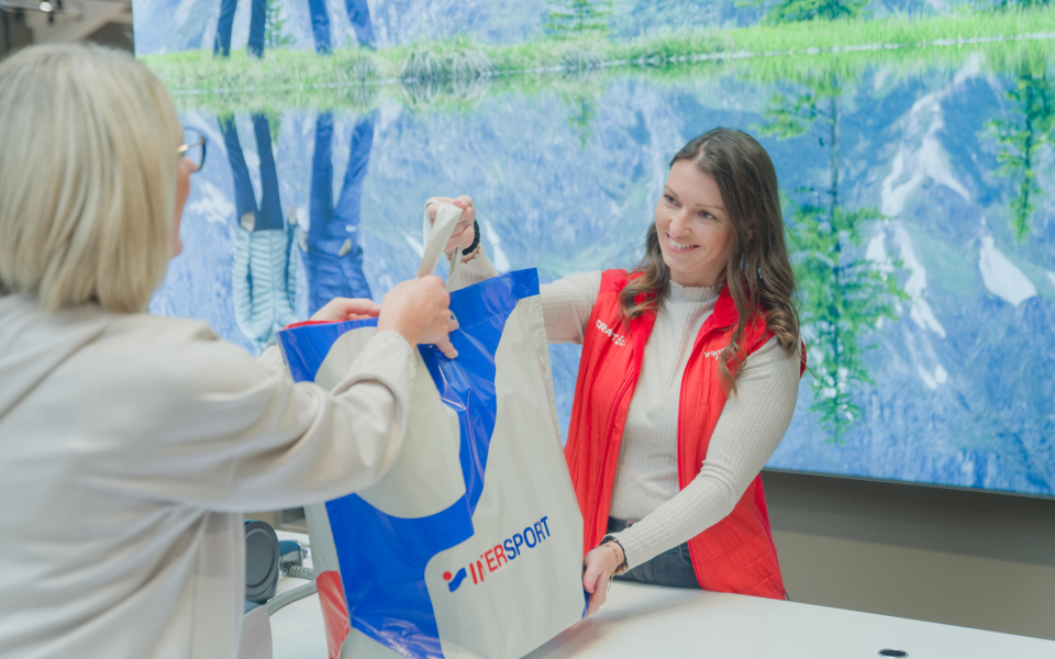 Verkäuferin gibt der Kundin ihren Einkauf in einer Tasche