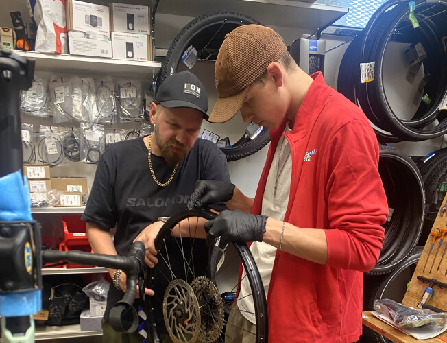 Ein Fahrradladenmitarbeiter in rotem Hemd montiert ein neues Mountainbike zum Verkauf.