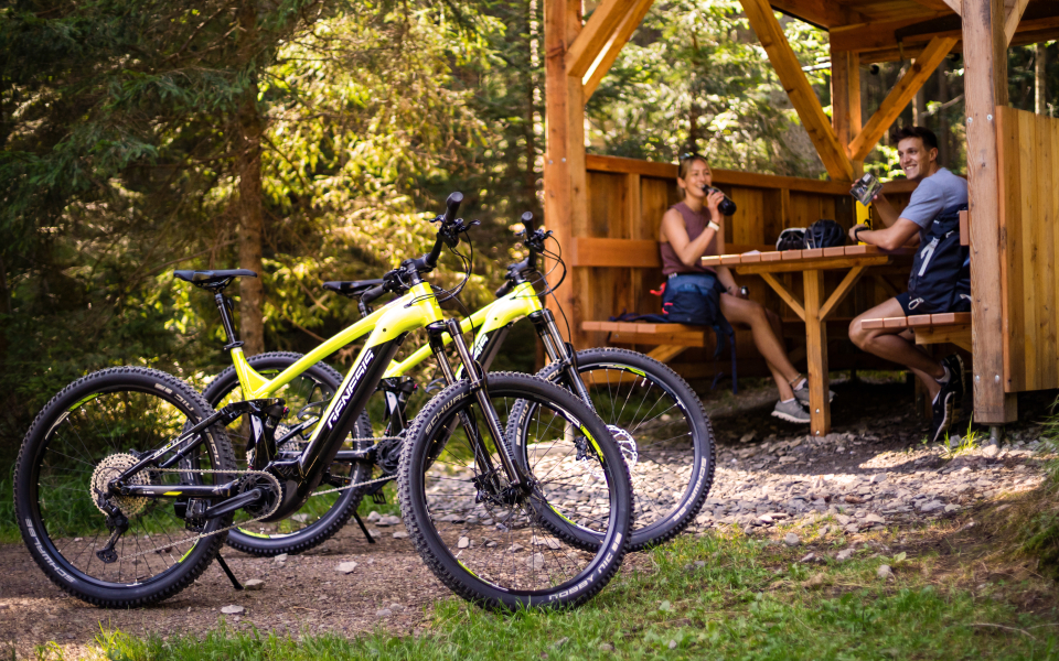 Zwei Fahrräder stehen vor einer Hütte, die Radfahrer sitzen in der Hütte