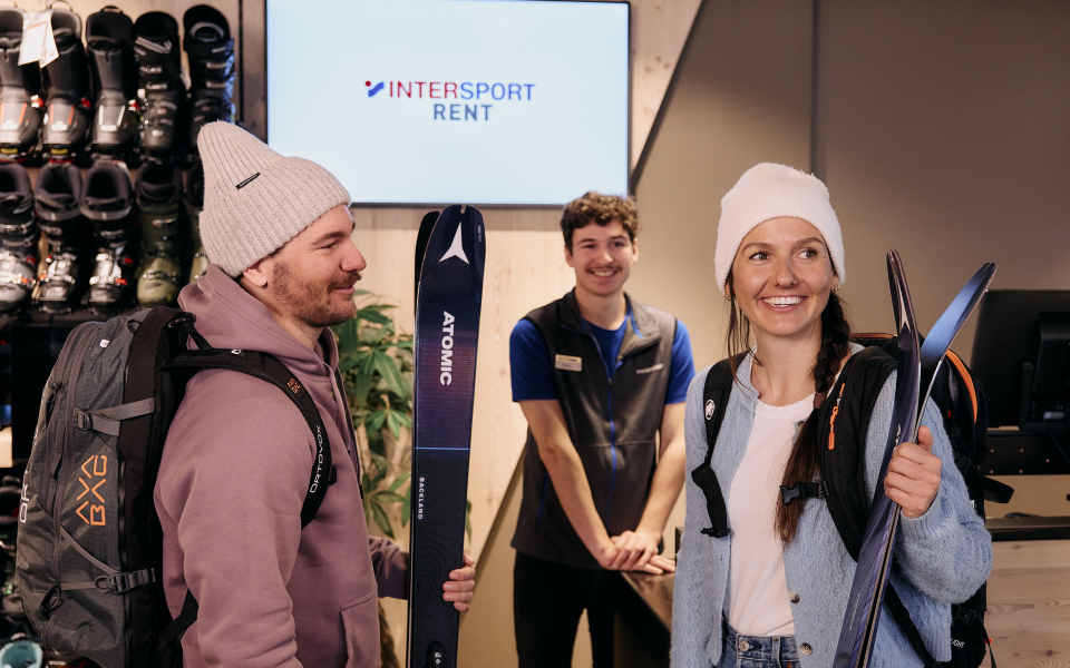 Drei Personen die glücklich wirken, eine Person hält Tourenski.